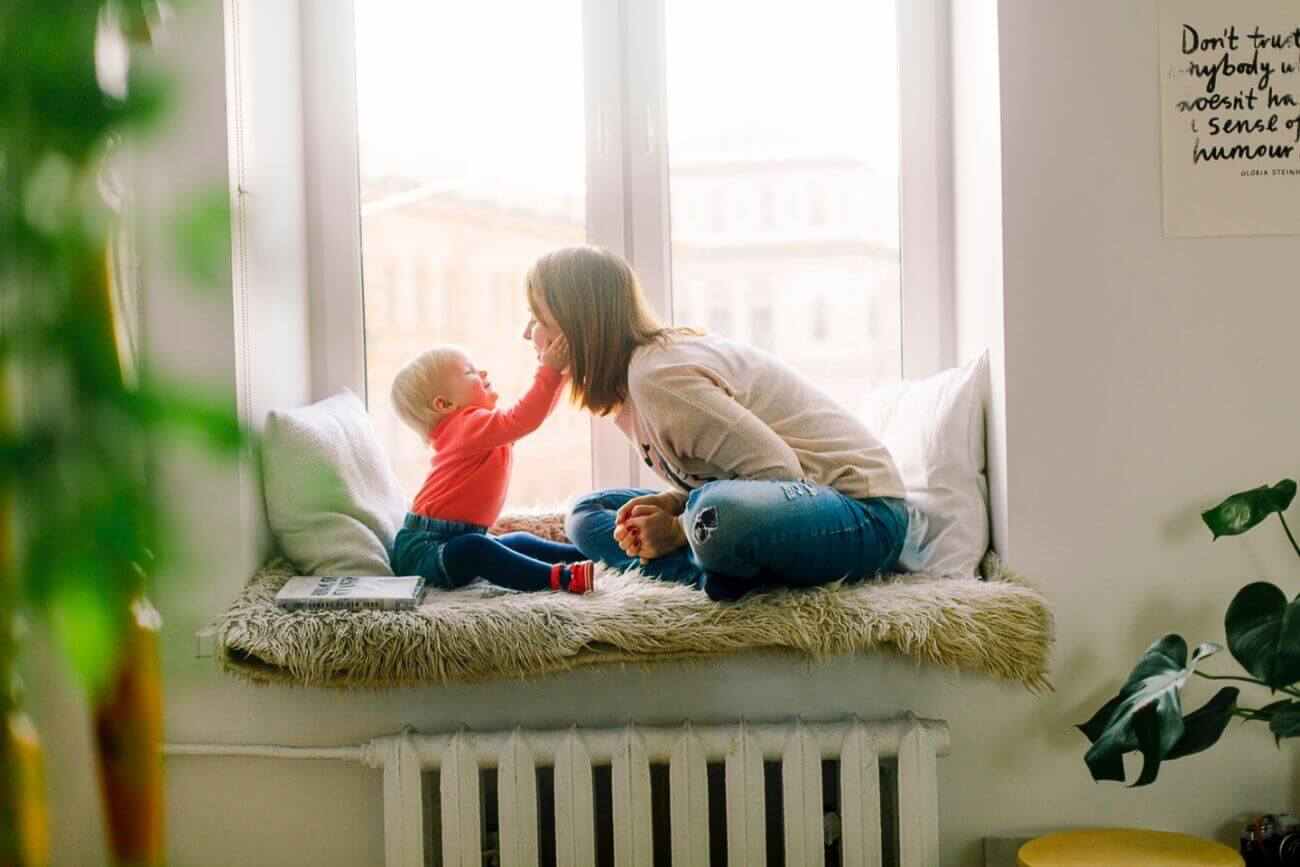 madre jugando con su hija junto a la ventana.